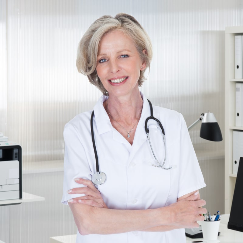 Portrait of confident female doctor standing arms crossed in clinic